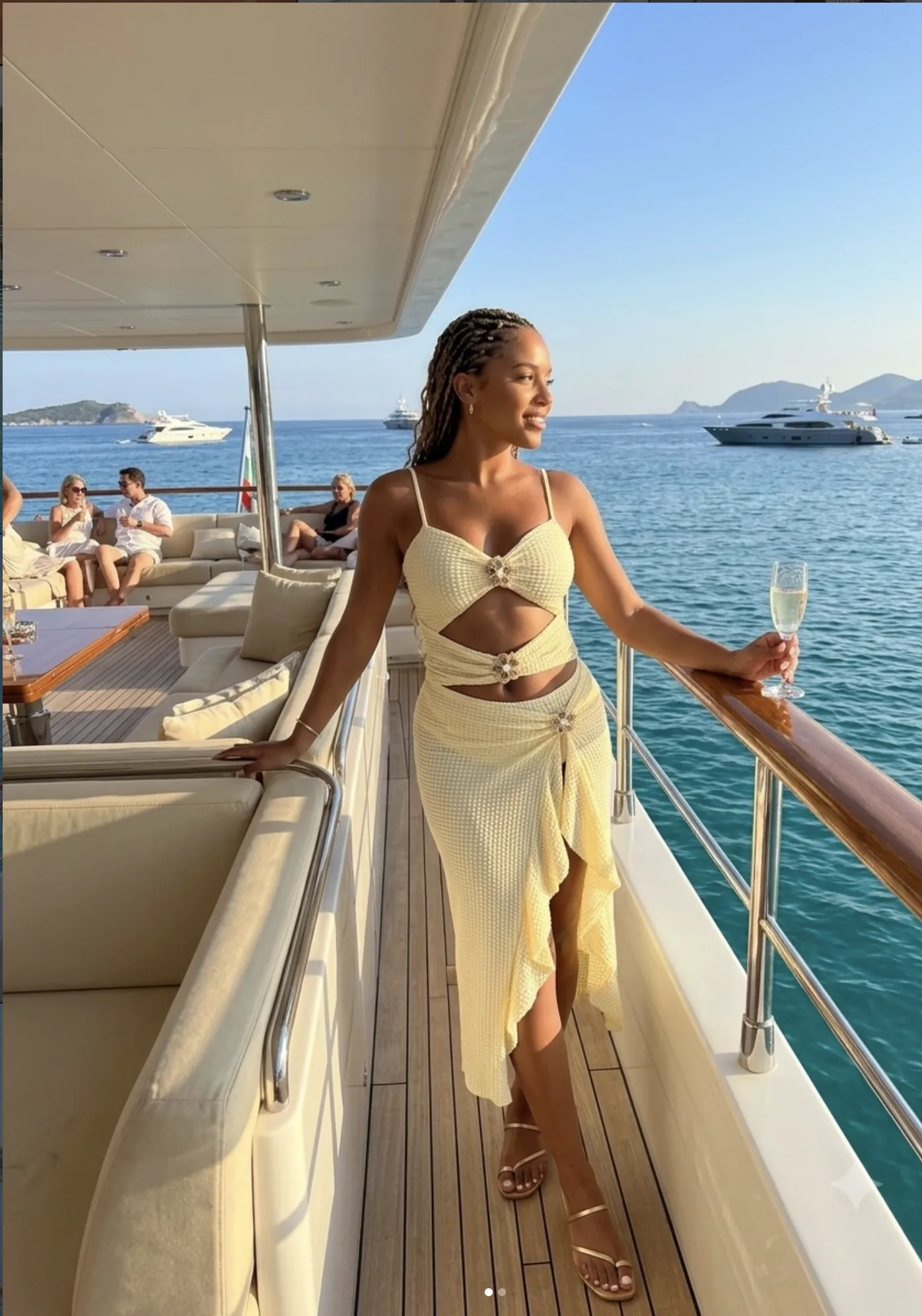 A woman in a butter-yellow cut-out set and sarong on the deck of a boat