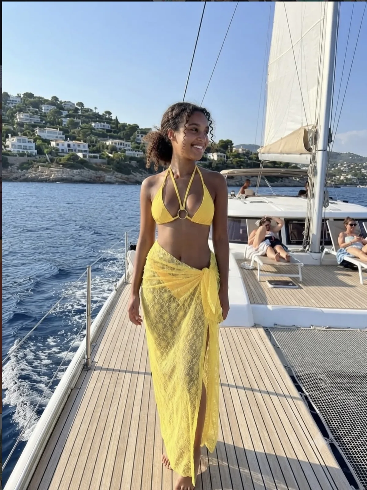 Woman in a yellow bikini and lace wrap sarong aboard a yacht